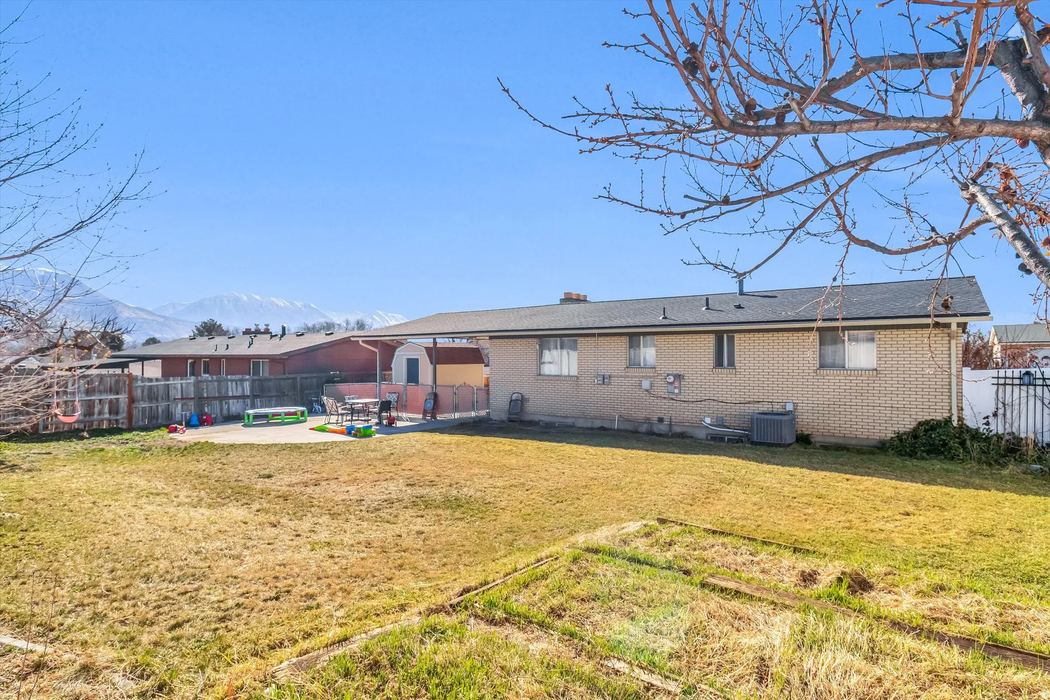 Rear view of house featuring a patio, a fenced backyard, a chimney, brick siding, and a mountain view
