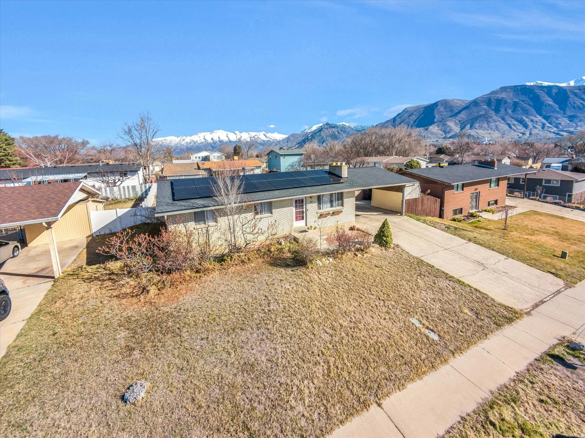Single story home featuring driveway, a carport, a mountain view, solar panels, and brick siding