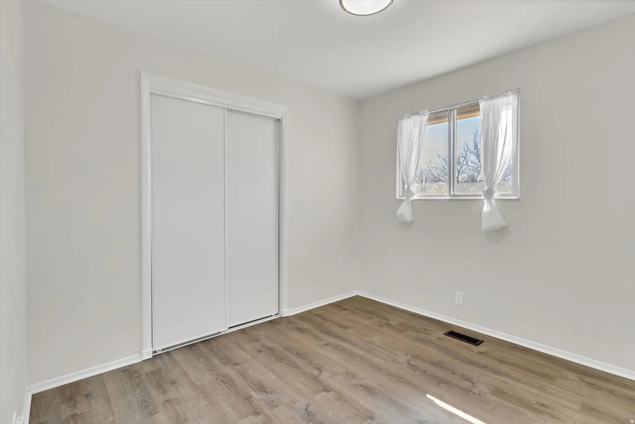 Unfurnished bedroom featuring light wood finished floors and a closet
