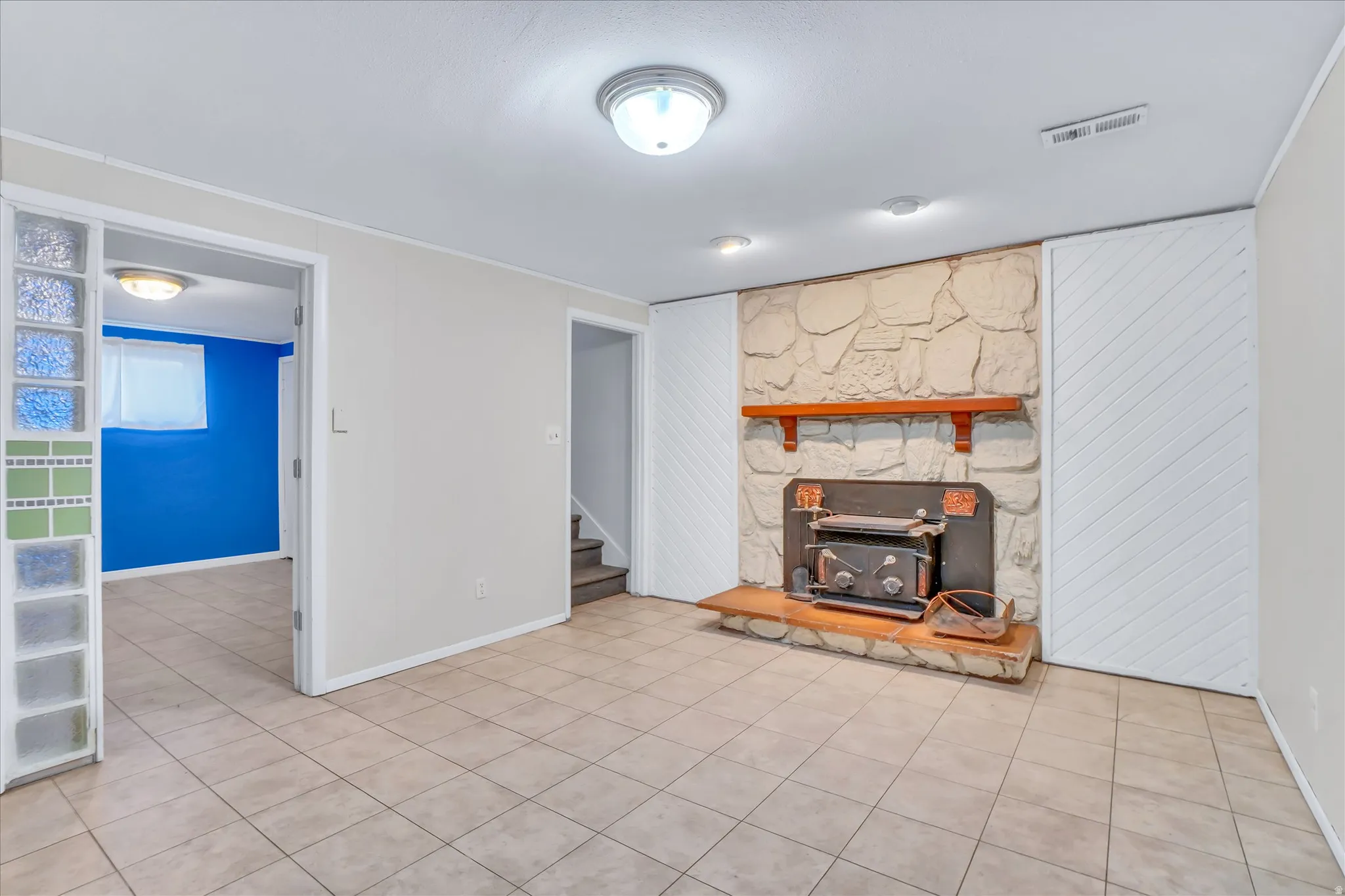 Tile flooring throughout, featuring a stone fireplace with a wood-burning insert and a wood mantel
