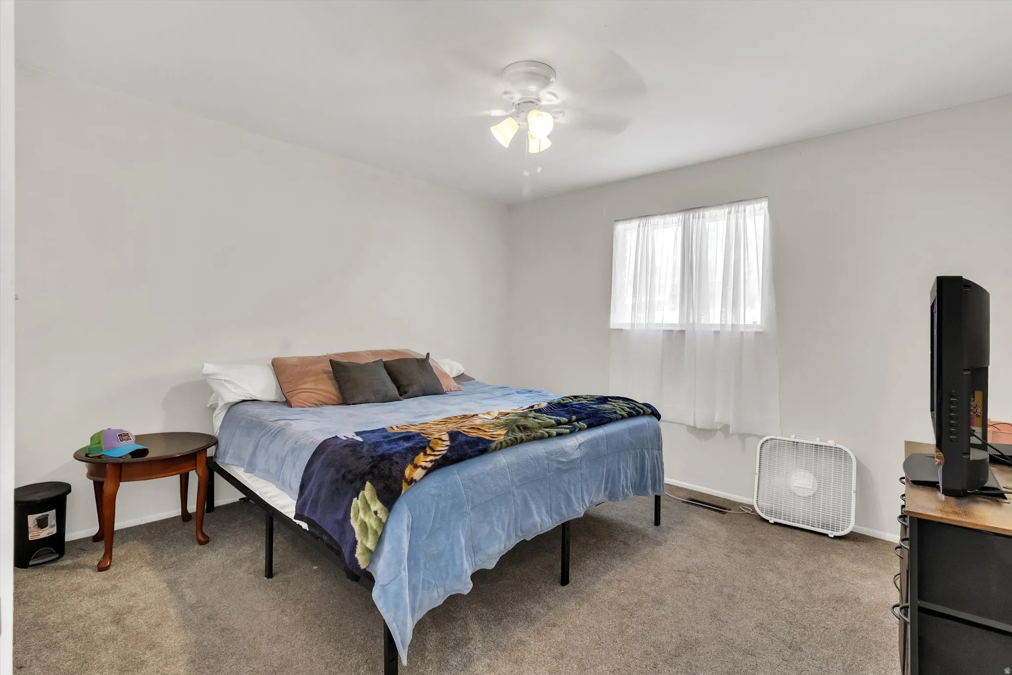 Carpeted bedroom with ceiling fan and baseboards