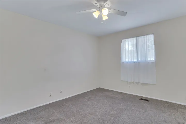 Neutral-toned room with carpet flooring and a ceiling fan with integrated lighting
