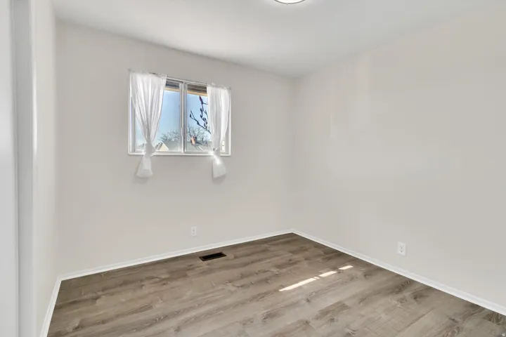 Room with a window, white walls, and wood-finish flooring