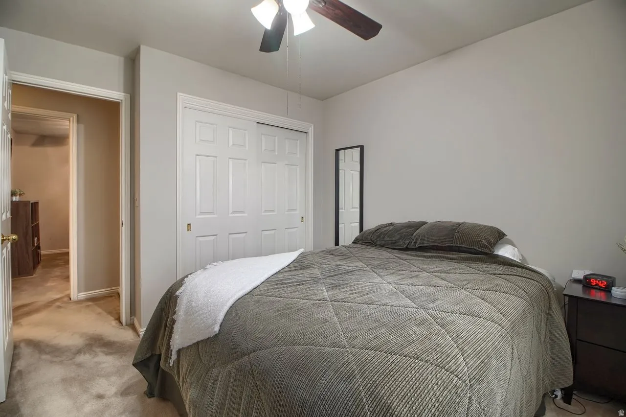 Carpeted bedroom featuring a closet and ceiling fan