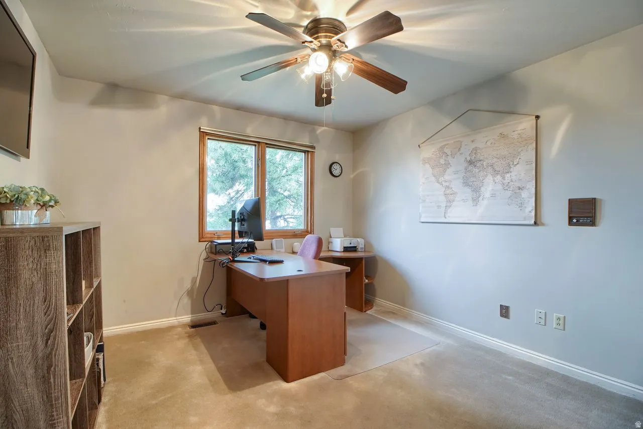 Office space with a ceiling fan and light colored carpet