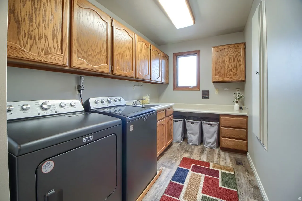 Laundry area featuring washing machine and dryer, cabinet space, and light wood-type flooring