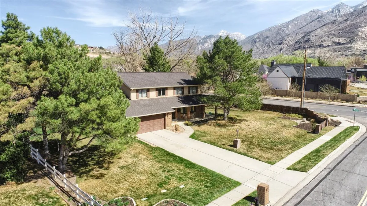 View of front facade featuring driveway, a front lawn, a garage, and a mountain view