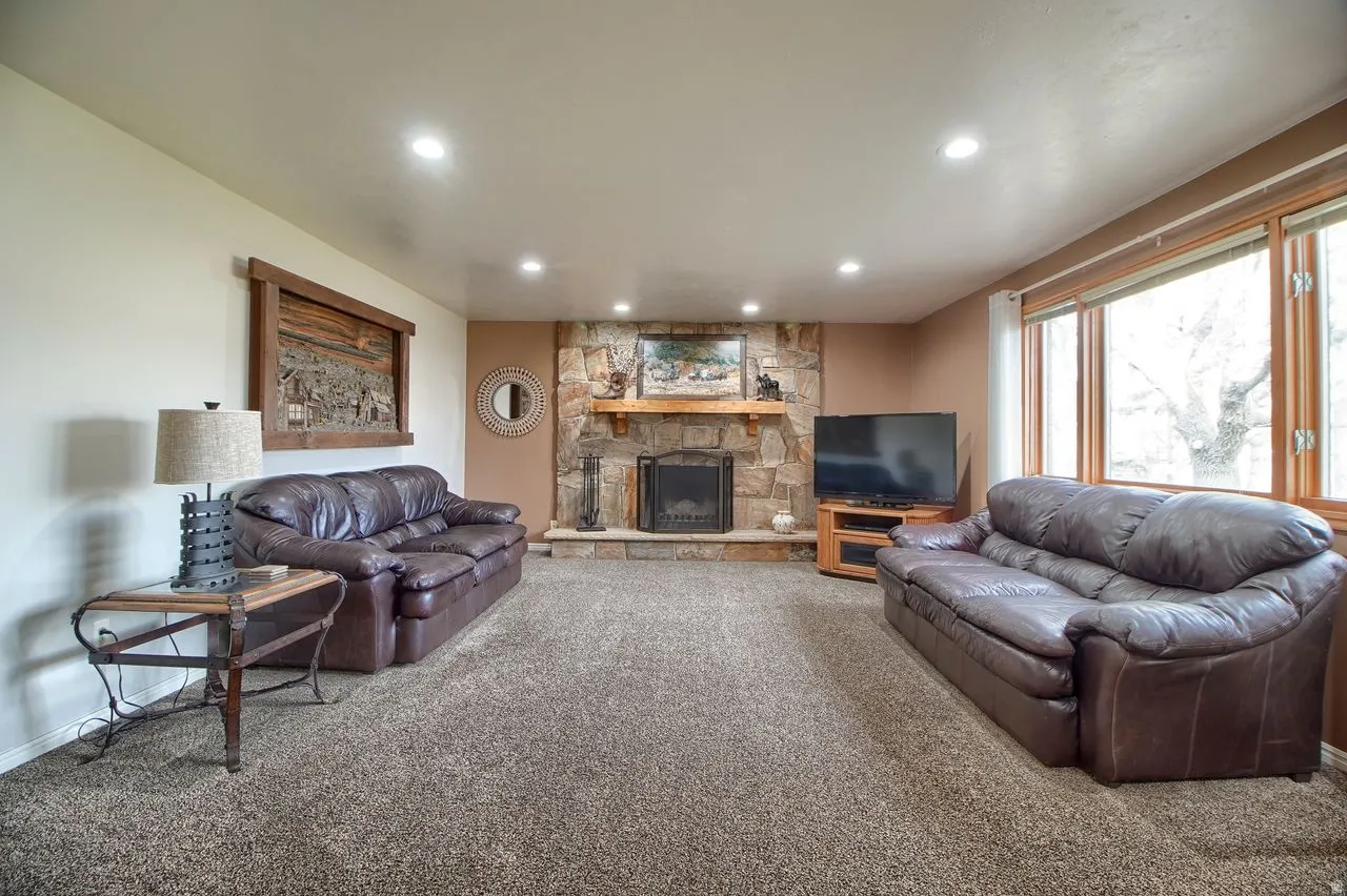 Living area featuring a stone fireplace, recessed lighting, and carpet
