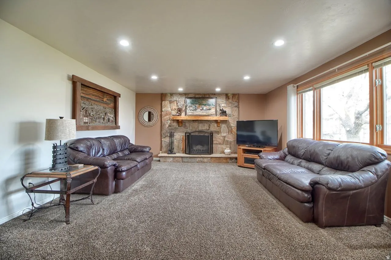 Carpeted living room with a stone fireplace and recessed lighting