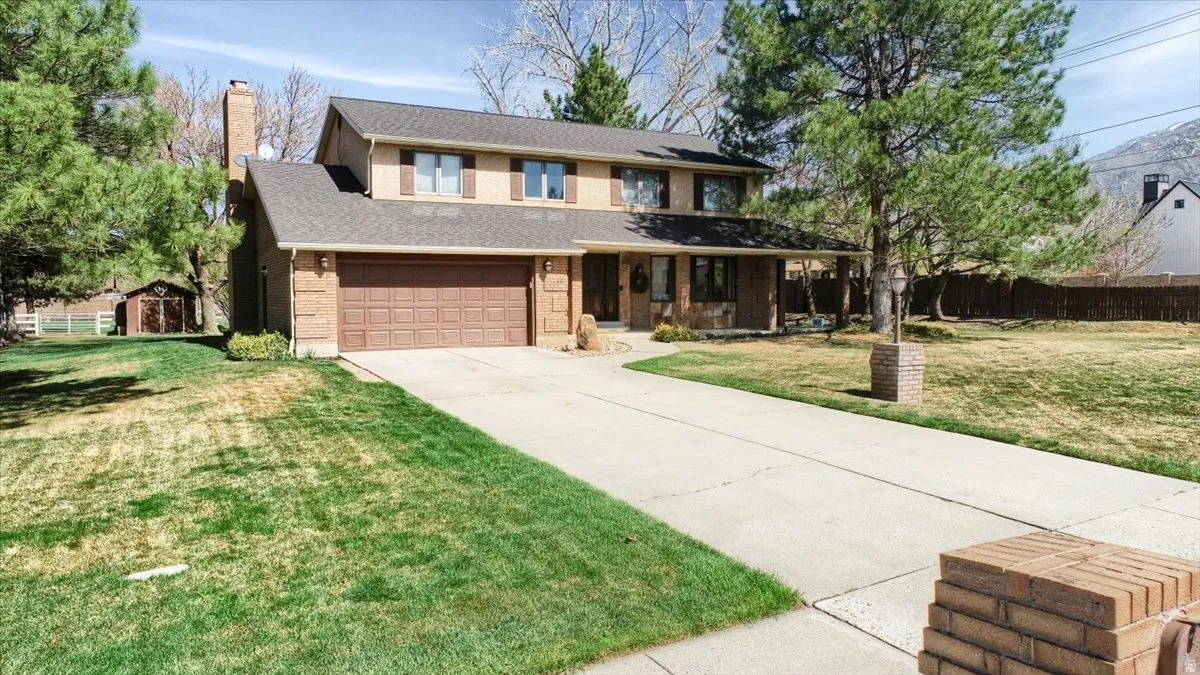 Traditional-style home with roof with shingles, a chimney, driveway, a porch, and brick siding