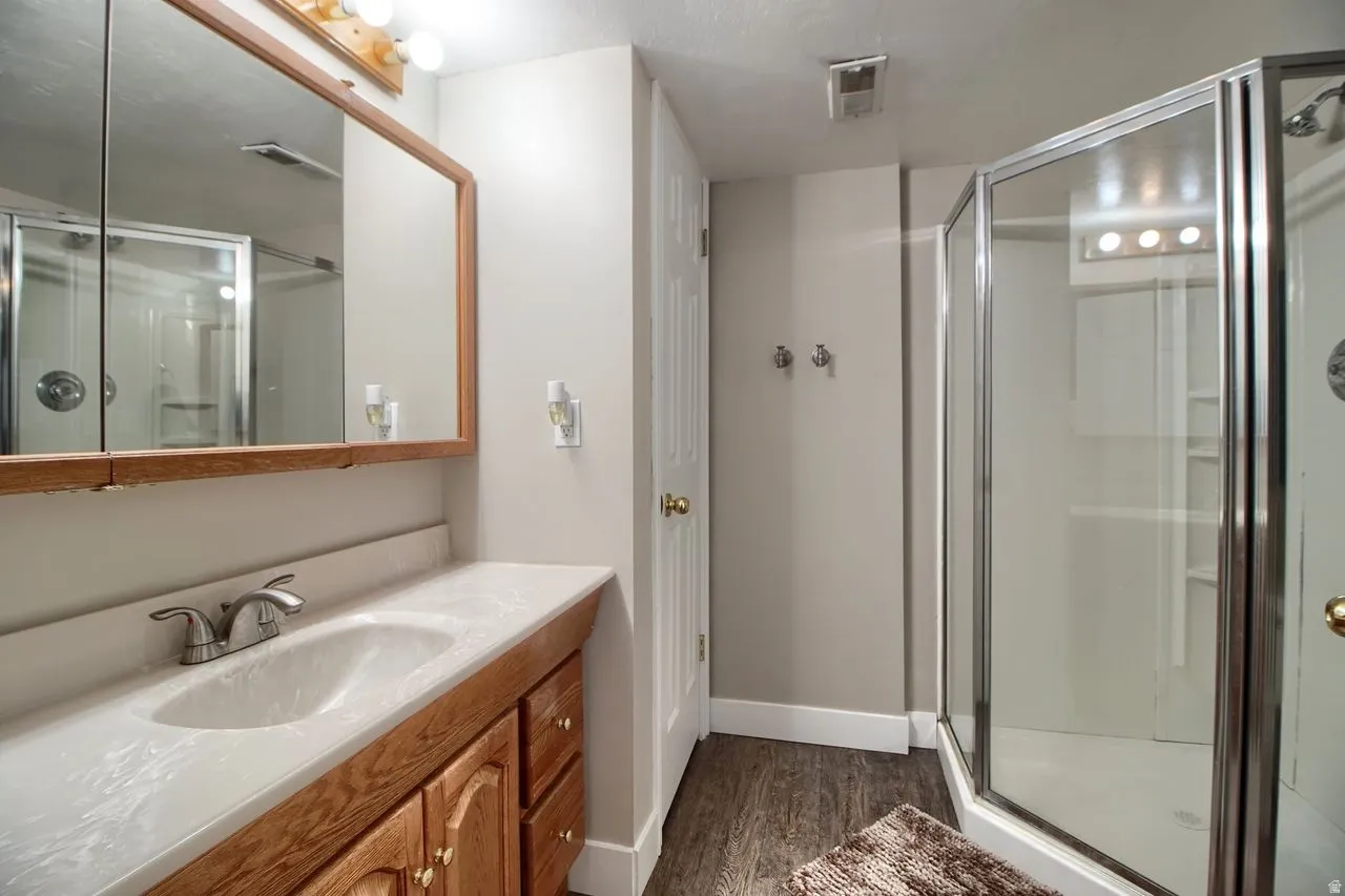 Bathroom with vanity, a shower stall, and dark wood finished floors