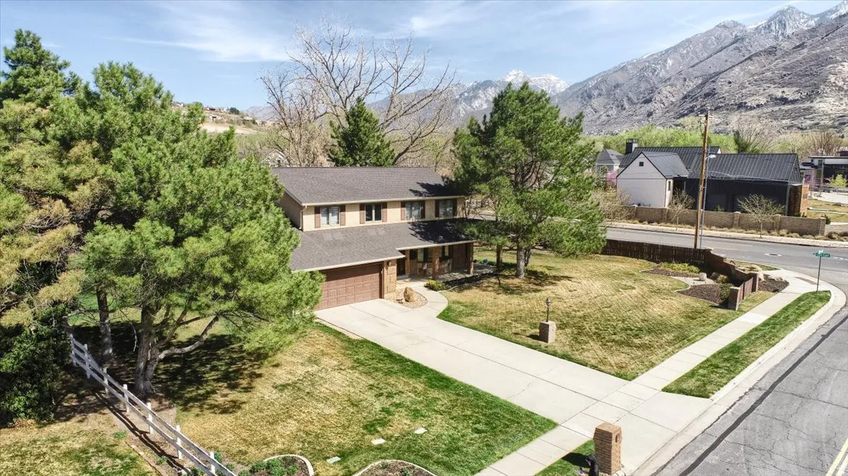 Traditional-style house with concrete driveway, a front yard, an attached garage, and a mountain view