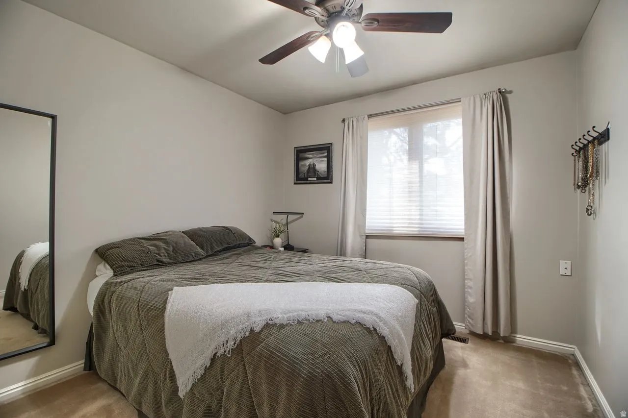 Carpeted bedroom with baseboards and a ceiling fan