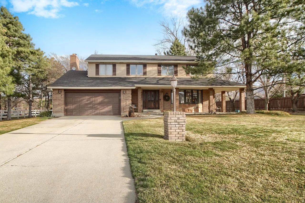 Traditional home featuring concrete driveway, brick siding, covered porch, and a chimney