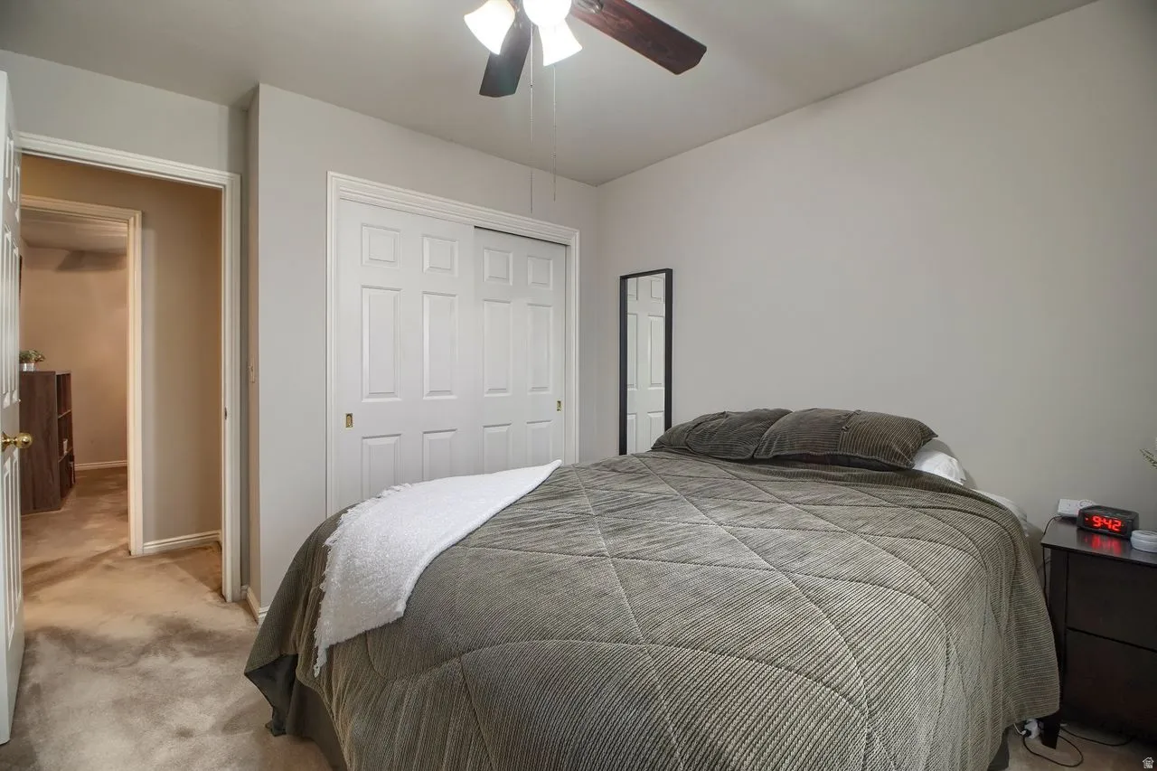 Carpeted bedroom featuring a closet and ceiling fan