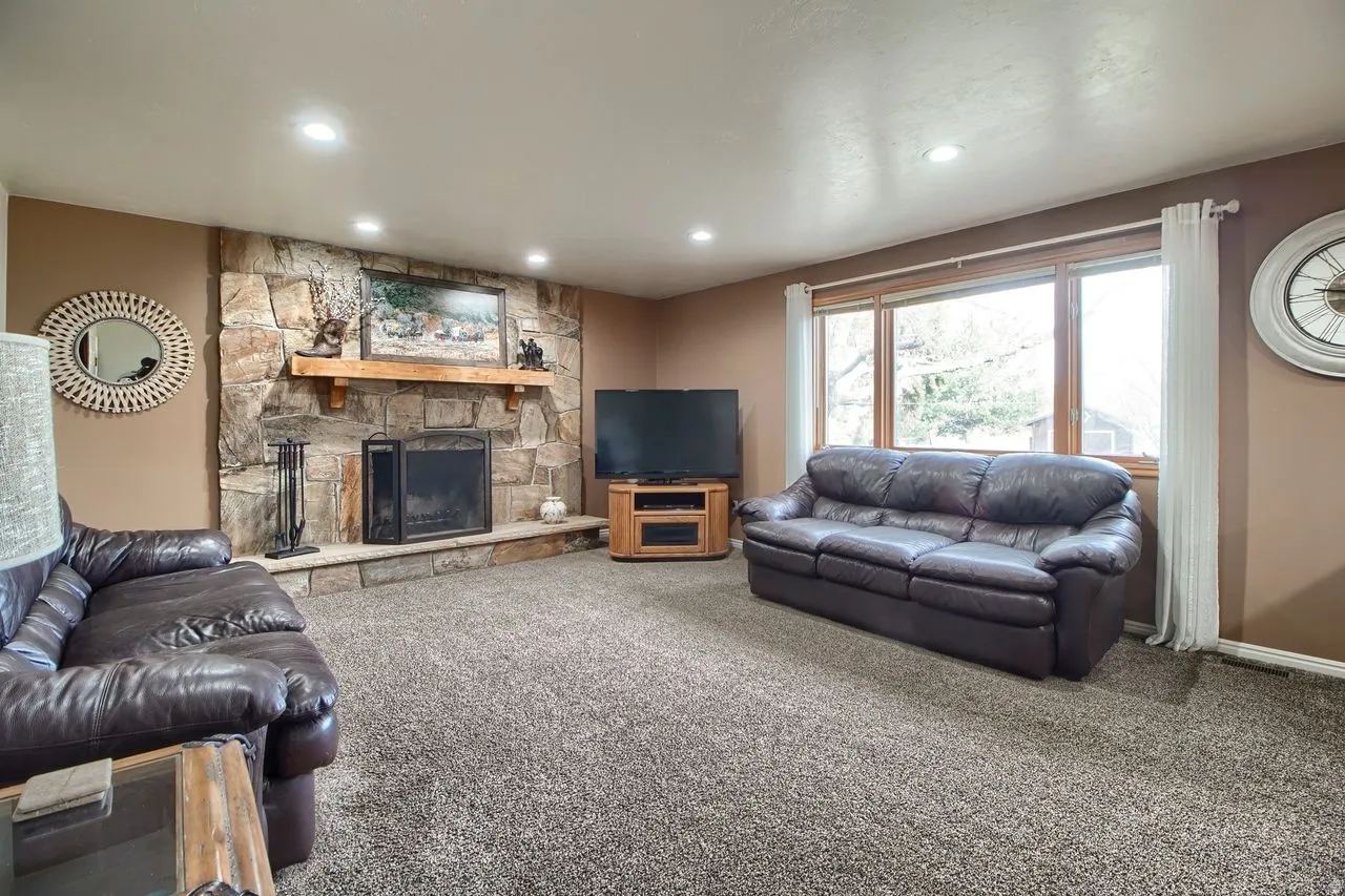 Living area with a stone fireplace, carpet floors, and recessed lighting