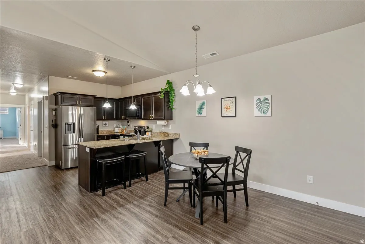 Dining space with lofted ceiling, dark wood-style floors, and a chandelier