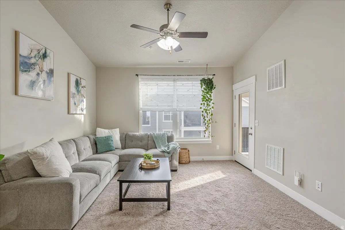 Living area featuring ceiling fan and light carpet