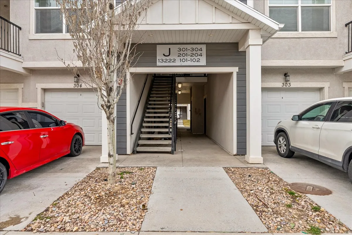 Doorway to property with board and batten siding, an attached garage, and stucco siding
