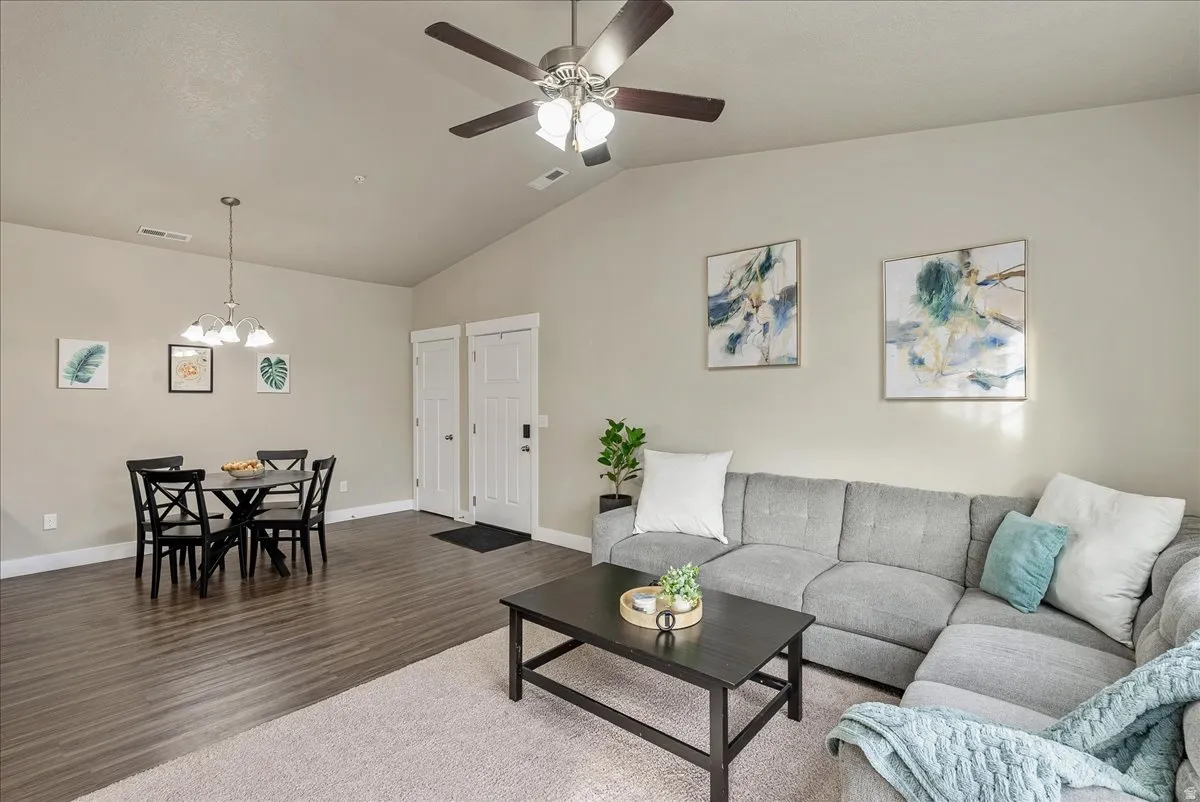 Living room featuring wood finished floors, lofted ceiling, a ceiling fan, and suspended lighting