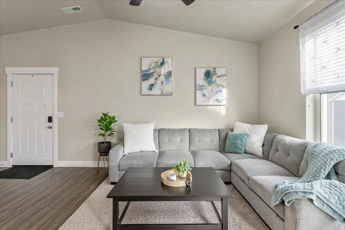 Living room featuring a ceiling fan, wood finished floors, and vaulted ceiling