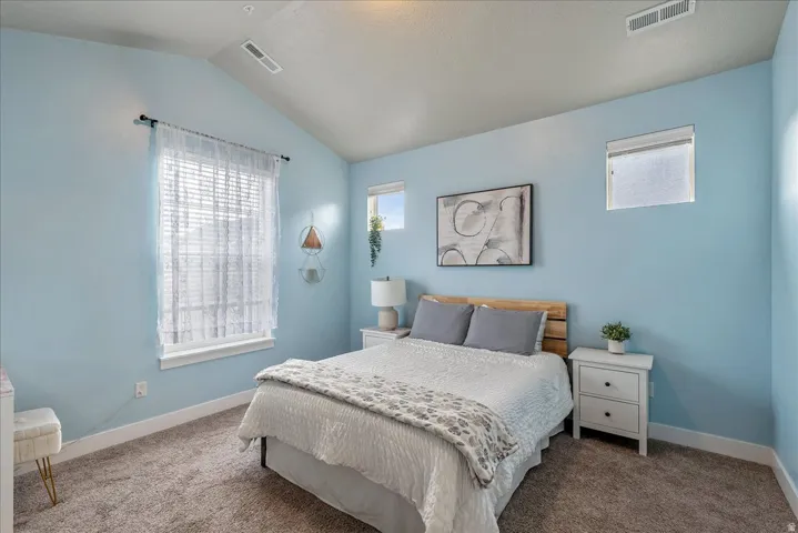 Carpeted bedroom featuring vaulted ceiling and baseboards