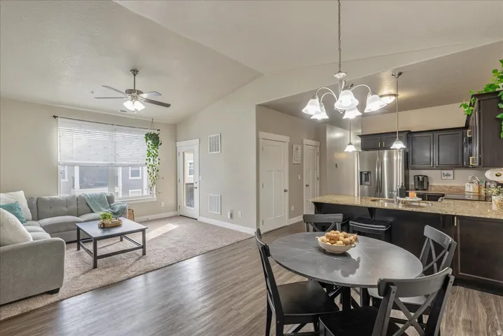 Dining space featuring a chandelier, light wood-style floors, a ceiling fan, and vaulted ceiling and open concept living.
