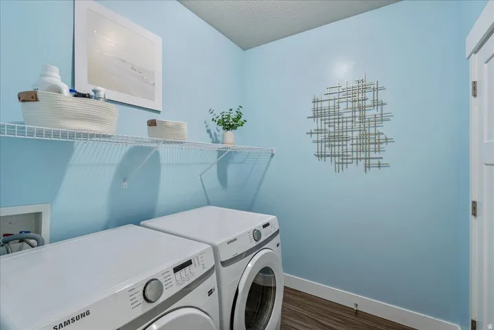 Laundry area with dark wood-style floors, washing machine and dryer, and a textured ceiling
