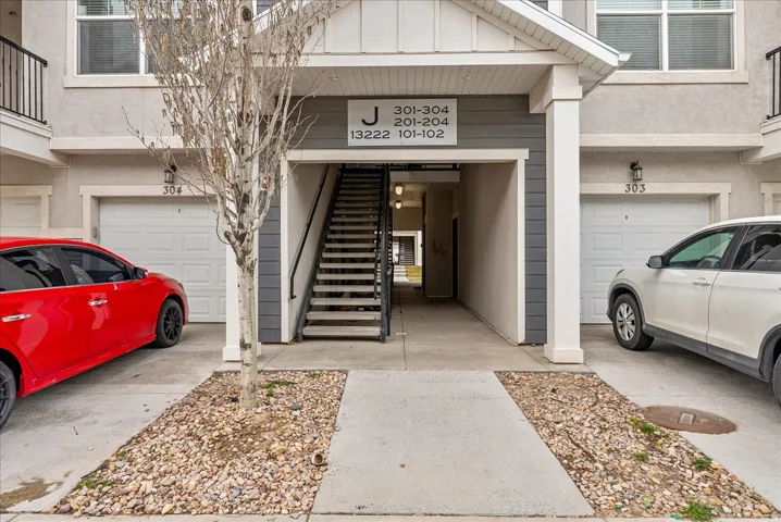 Doorway to property with board and batten siding, an attached garage, and stucco siding