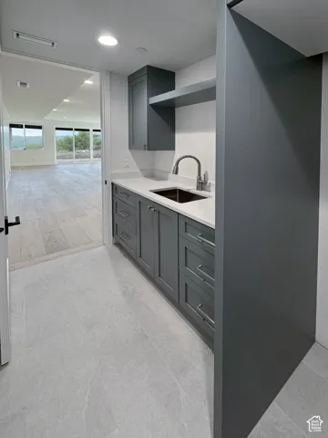 Bar area featuring light stone counters, gray cabinetry, and recessed lighting