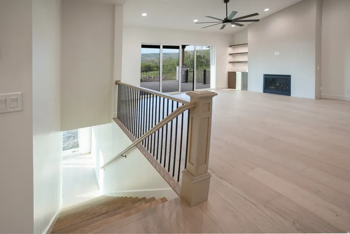 Stairs featuring wood-type flooring, recessed lighting, a glass covered fireplace, and ceiling fan