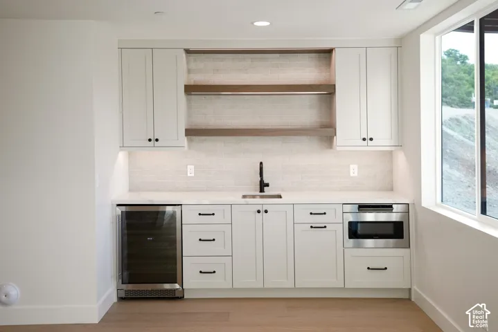 Bar featuring open shelves, beverage cooler, white cabinetry, tasteful backsplash, and recessed lighting