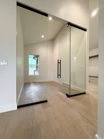 Empty room with light wood-style floors, vaulted ceiling, and recessed lighting