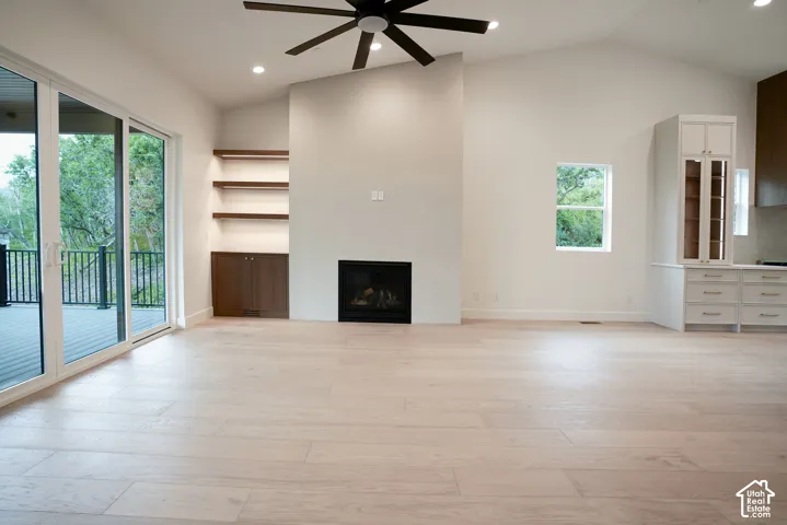 Unfurnished living room with ceiling fan, vaulted ceiling, a fireplace, light wood finished floors, and recessed lighting