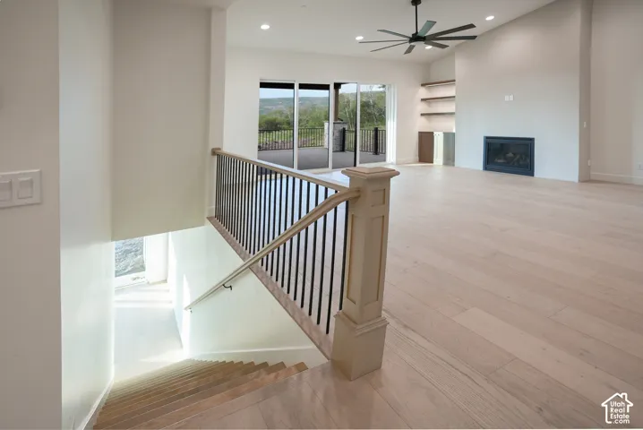 Stairs featuring wood-type flooring, recessed lighting, a glass covered fireplace, and ceiling fan