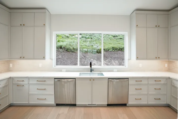 Kitchen with dishwasher, tasteful backsplash, light wood finished floors, and light stone countertops