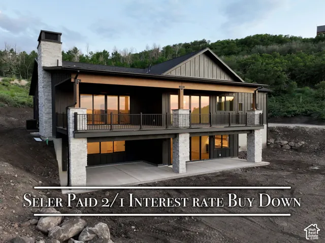 Multi-level exterior featuring stone veneer masonry, vertical siding, an elevated deck with metal railing, and a covered lower-level concrete patio