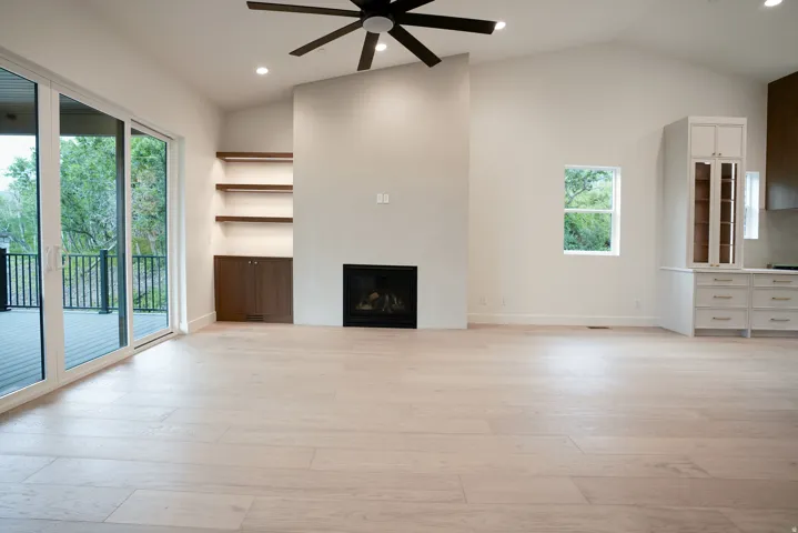 Unfurnished living room with ceiling fan, vaulted ceiling, a fireplace, light wood finished floors, and recessed lighting