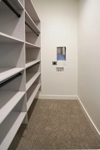 Walk in closet with dark colored carpet