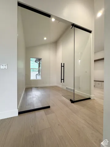 Empty room with light wood-style floors, vaulted ceiling, and recessed lighting