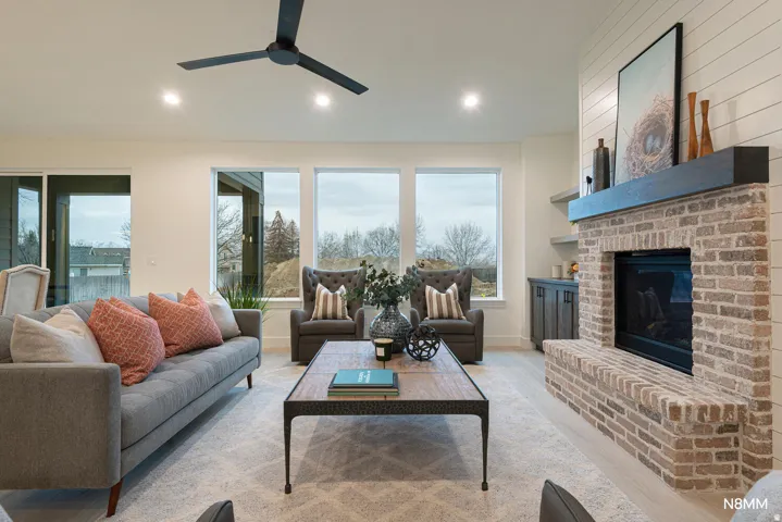 Living room with light wood-style floors, a fireplace, ceiling fan, and recessed lighting