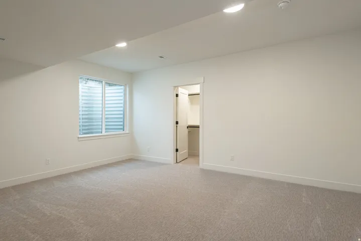 Additional living space with light carpet and recessed lighting