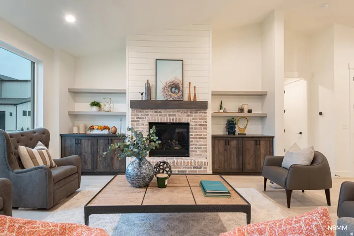 Living room featuring a fireplace, lofted ceiling, light wood-style flooring, recessed lighting, and built in features
