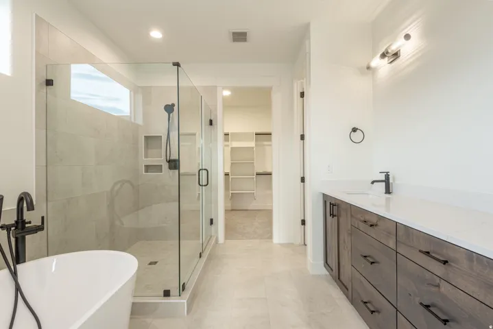 Full bathroom featuring a freestanding tub, a stall shower, a spacious closet, vanity, and recessed lighting