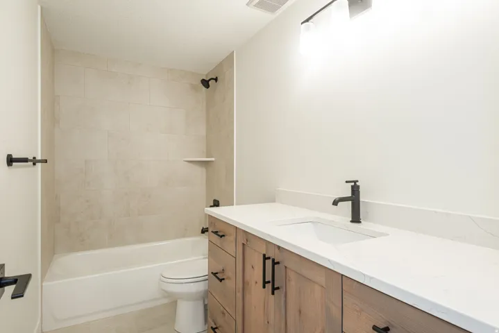 Bathroom featuring vanity, shower / washtub combination, light tile patterned flooring, and a textured ceiling