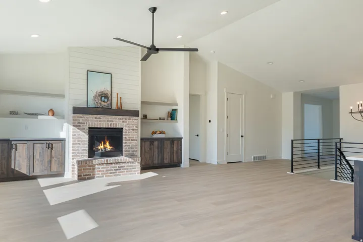 Unfurnished living room featuring light wood finished floors, lofted ceiling, recessed lighting, a fireplace, and ceiling fan