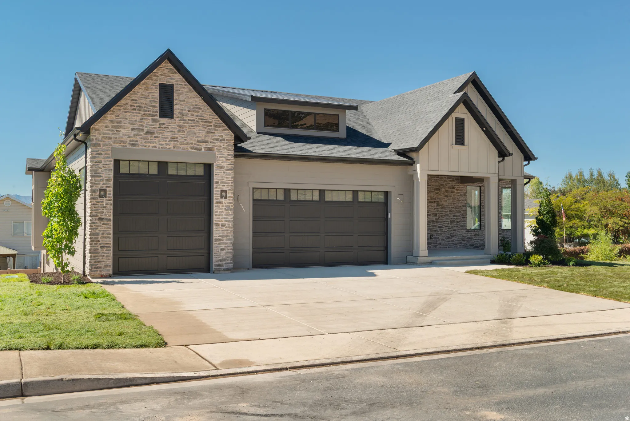 View of front facade featuring driveway, a shingled roof, a garage, and board and batten siding