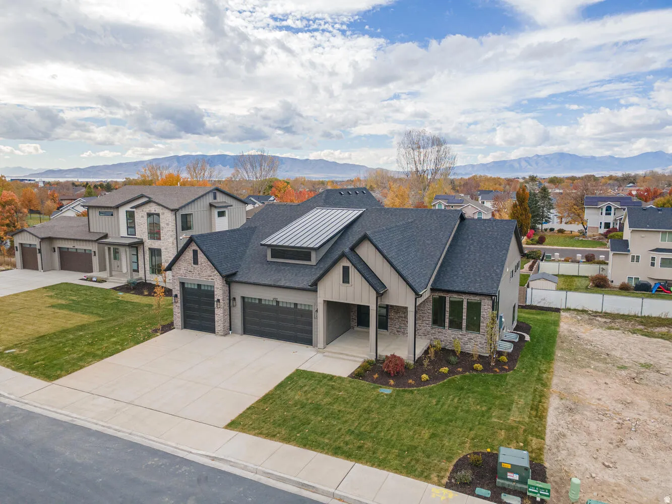 Modern inspired farmhouse featuring stone siding, a residential view, a mountain view, a garage, and a porch