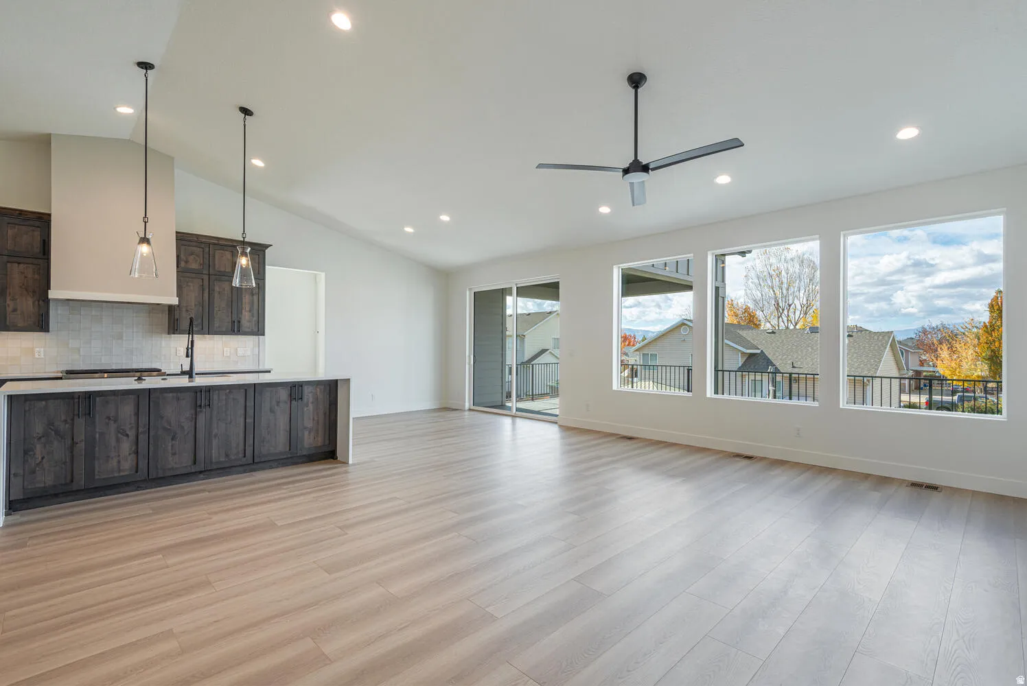 Unfurnished living room with light wood-type flooring, a ceiling fan, recessed lighting, and vaulted ceiling