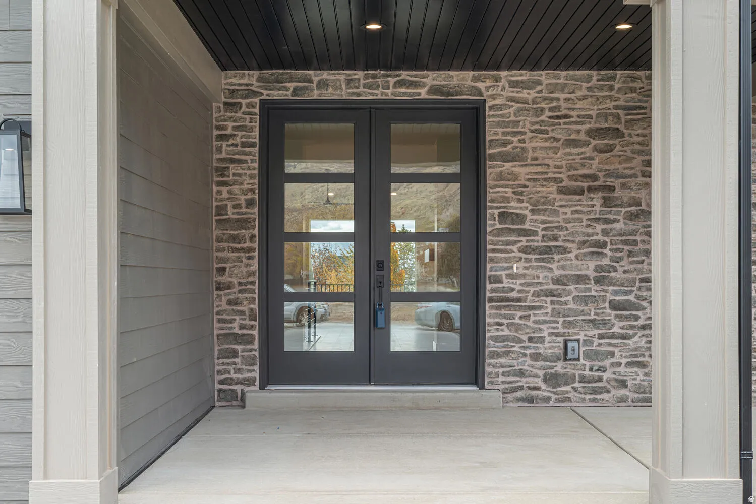 Entrance to property featuring french doors, stone siding, and brick siding